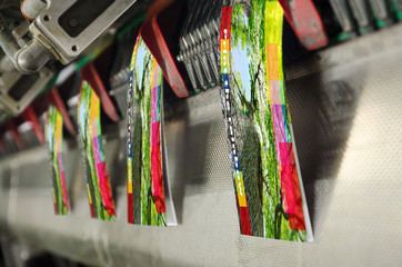 Brochure and magazine stitching process. Close-up of the offset conveying process of a...