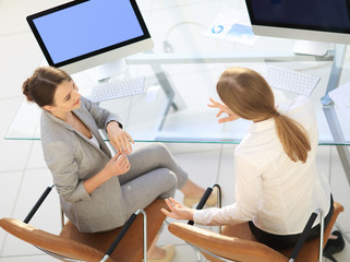 view from the top rear.business woman talking with a colleague sitting near the desktop
