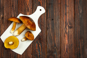 White mushroom. Autumn white mushrooms on cutting board on wooden background.