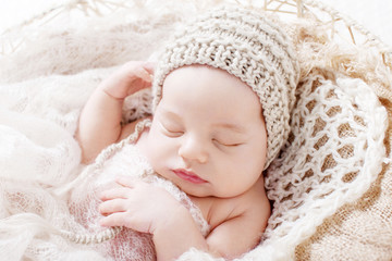 Sweet newborn baby sleeping.  Newborn boy 3 weeks old lying in a basket with knitted plaid. Portrait of pretty  newborn boy. Closeup image