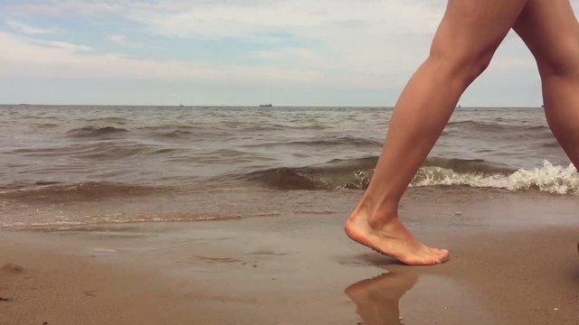 Young beautiful girl is walking along the sandy beach.Feet close-up.