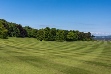 Edinburgh, Scotland, UK - June 14, 2012: The wide green lawns of Dalmany house, mansion and castle in Tudor revival style lead to Firth of Forth. Blue sky.