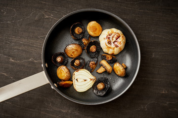 delicious fried mushrooms on a hot pan on an old wooden black table