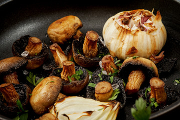 delicious fried mushrooms on a hot pan on an old wooden black table
