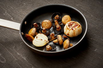 delicious fried mushrooms on a hot pan on an old wooden black table