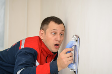 Home interior renovation handyman smoothing down a white wall with a sandpaper tool