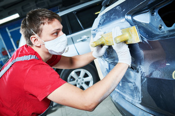 auto repairman grinding automobile body