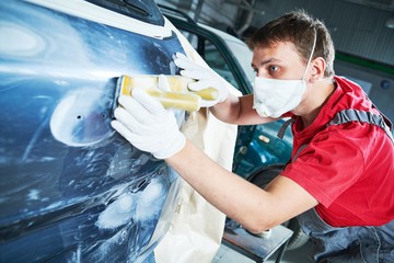 auto repairman grinding automobile body