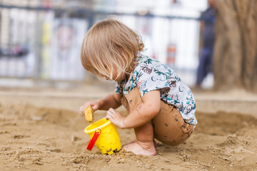 Little girl, child playing with sand. Blondes Mädchen, Kleinkind spielt mit Sand. 