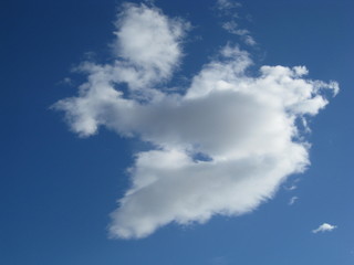 Nube blanca y gris en forma de corazón roto, aislada en cielo azul