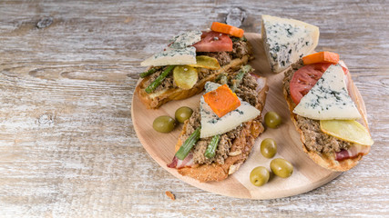 Italian sandwiches with pate, vegetables and cheese on a wooden background. Mediterranean traditional cuisine
