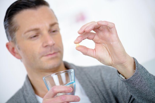 Sick Man Holding A Pill With A Glass Of Water