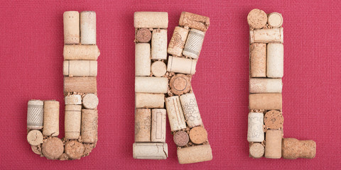 Alphabet letter J, K, L made of wine corks on red Bordeaux background. ABC set, Burgundy color and wine berry