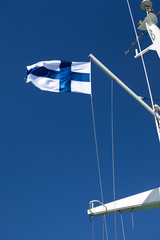 National flag of Finland flying on mast of ferry against blue sky, vertical image