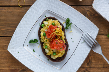 Smorrebrod, traditional Danish open sanwiches, dark rye bread with salmon, cream cheese and capers. Top view