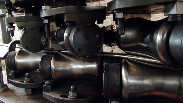Close-up of metal-rolling machines for production metal steel pipes in factory. Seamless technology for production of profile pipe.