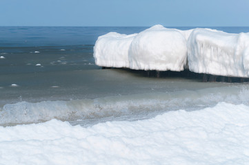 Fototapeta na wymiar Ice on breakwaters in the sea, sea waves in the icy snow slush. Sea coast in winter.
