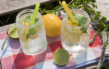 Cold refreshing drink in glass jar with slices of lemons and limes.