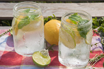 Cold refreshing drink in glass jar with slices of lemons and limes.