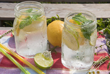 Cold refreshing drink in glass jar with slices of lemons and limes.