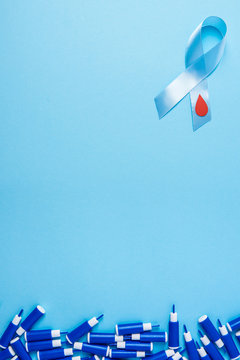 blue ribbon awareness with red blood drop and line of lancets on a blue background, World diabetes day