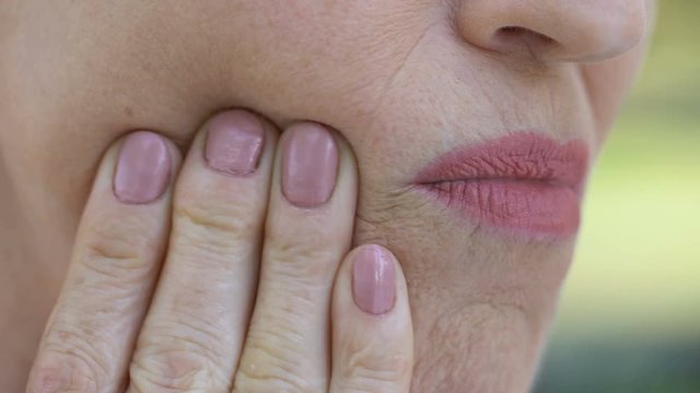 Retired lady feeling discomfort in mouth, inflammation of gums, periodontitis