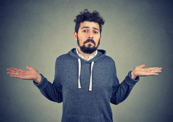 Portrait of a young man shrugging shoulders feeling clueless