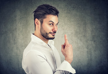 Smart sly sales man holding finger up