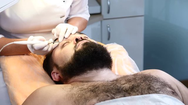Brutal darkhaired man gets medical mole and Papillomas removing procedure in medical centre.Doctor removes papilloma off male eyelid. 4k
