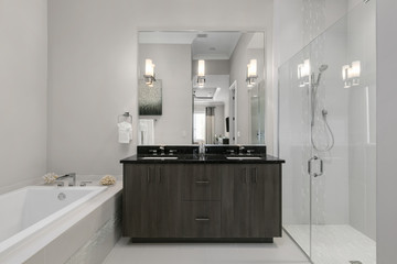 clean white bathroom with his and hers sinks, dark wood cupboards, bath and shower 