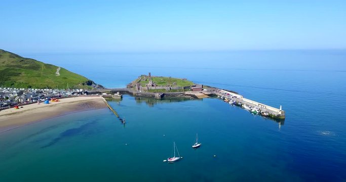 Drone flying over Peel Castle on Isle of Man, landmark building in Peel on the Isle of Man, originally constructed by Vikings. Aerial view of charming sea village and old monument seen from the sky