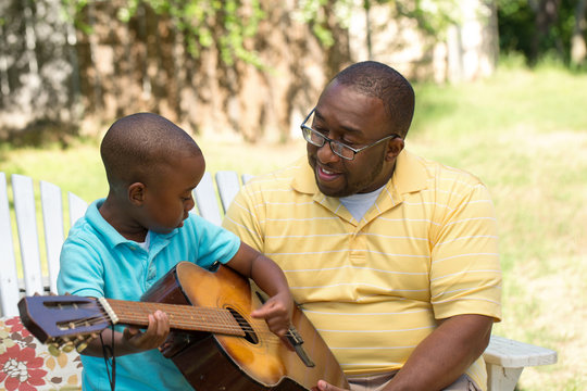 Father teaaching his his son to play the guitar.