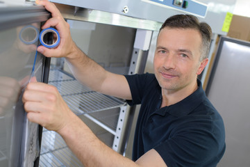 repairmanrepairing refrigerator in kitchen room