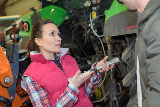 young worker checks the pressure of the tractor engine