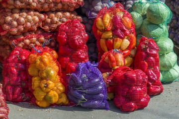 Fresh young Bulgarian peppers and cabbage and onions and potatoes in bags, on the counter
