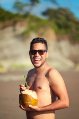 Junger Mann mit Cocktail am Strand.