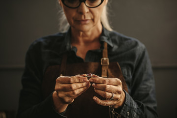 Woman goldsmith inspecting silver ring - obrazy, fototapety, plakaty