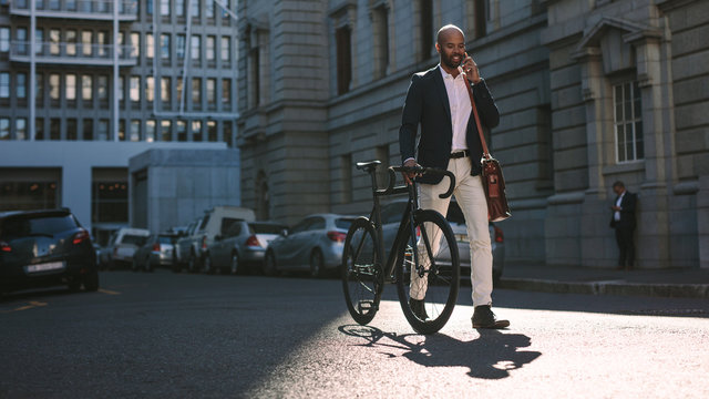 Businessman going to office by bicycle and talking on phone