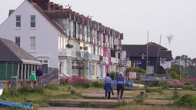 Pretty and colorful rowhouses or cottages line a beach at a seaside resort in England.