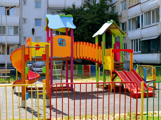 Colorful children's playground with slides and swings in the courtyard of a multi-storey...