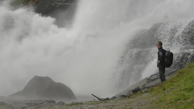 Caucasian Traveler with Backpack on the Edge of the Waterfall. Slow Motion Footage