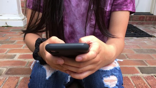 Teen Girl Texting On The Front Steps