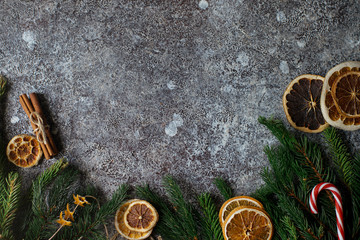 Christmas or New Year flat lay home decor, dry oranges, cinnamon, candies and fir branches on concrete background. Cozy winter homely scene, top view, copy space