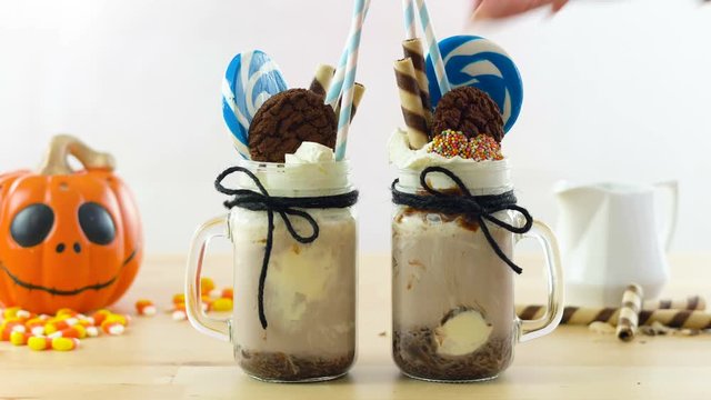 On-trend Happy Halloween theme freak shakes chocolate milkshakes decorated with candy, cookies and lollipops.