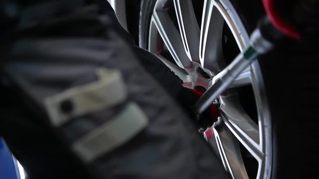 Car Mechanic Attaching Car Wheels Back to the Vehicle