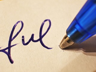 Fototapeta premium drawing a smiley with blue ballpoint pen on white paper, closeup