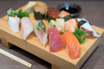 Close-up sushi and sashimi mixed on wooden plate on black wooden table. Japanese food.