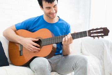 Obraz premium Asian young man hands playing acoustic guitar at home. Enjoy playing acoustic guitar for relax in holiday.
