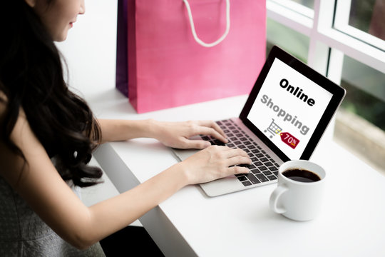 Young woman holding credit card and using laptop computer in cafe. Online shopping concept