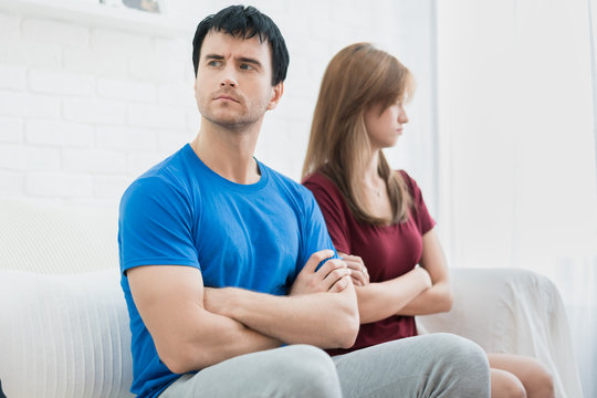 Unhappy couple not talking after an argument in sofa at home. People, relationship difficulties and family concept.